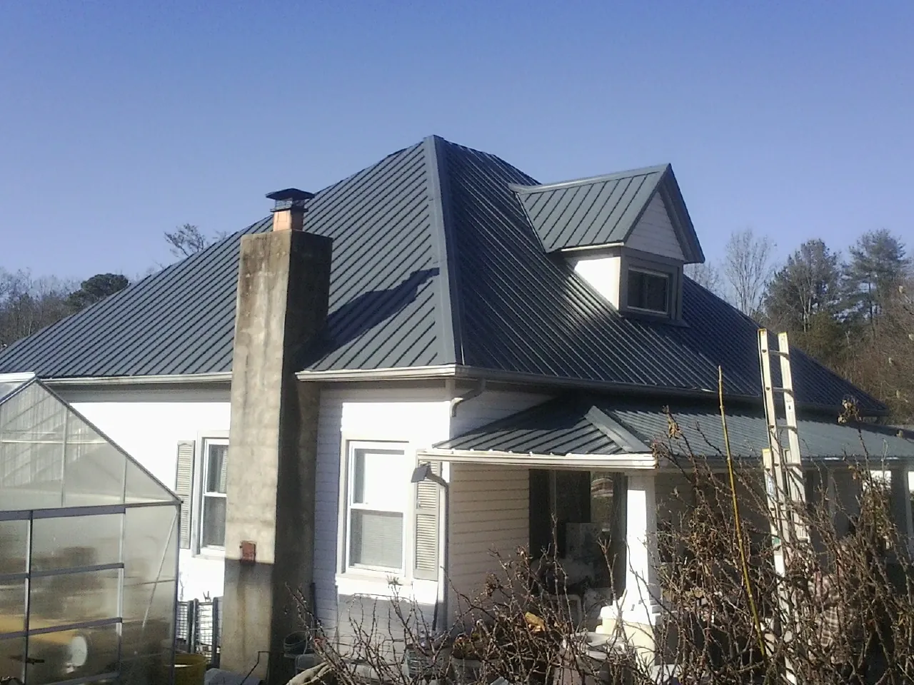 Dark blue standing seam metal roof on a white farmhouse with dormer — Slate & Tile Roof Repair by Roofing Brothers in Millerstown