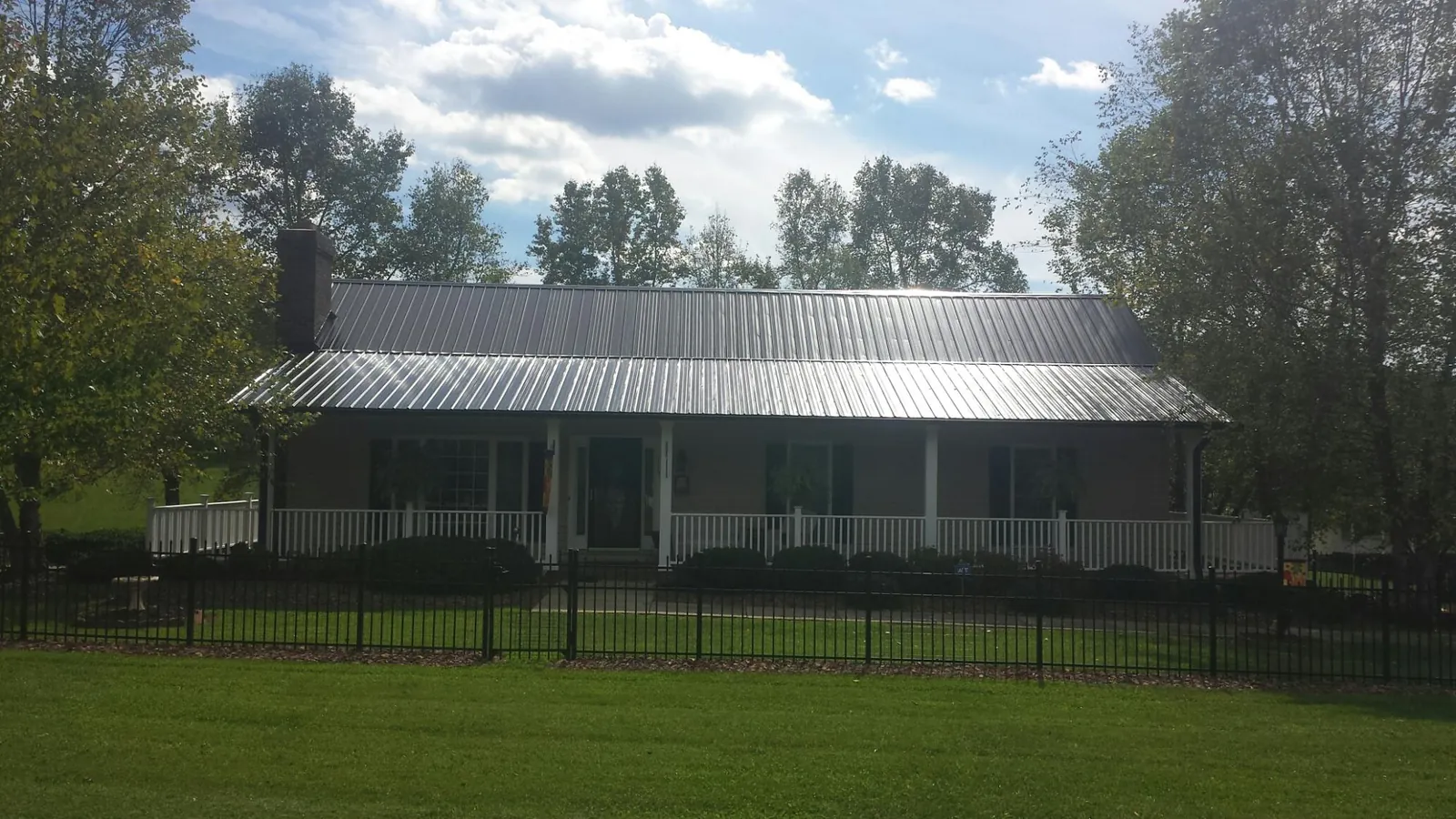 Gray metal roof on a brick ranch with a full width front porch — Gutter Guard Installation work by our crew in Millerstown