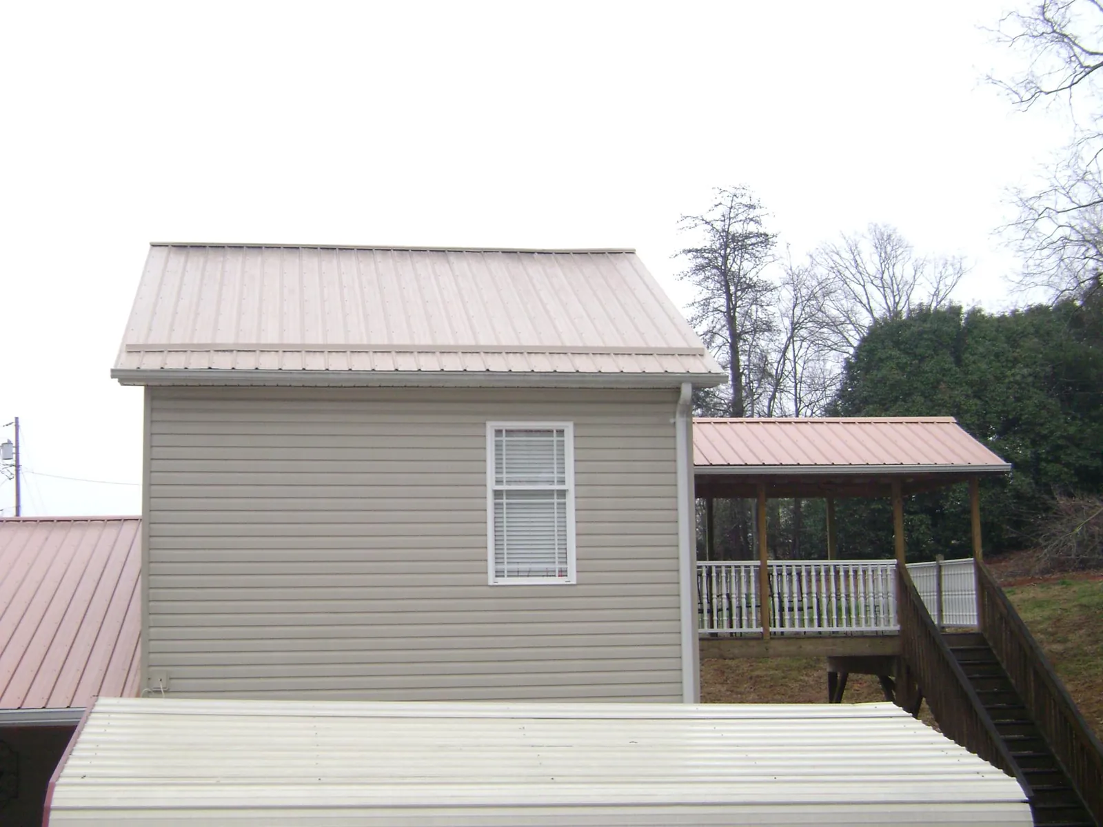Tan metal roofs on a two story addition and attached porch, from a Roof Replacement job in Millerstown