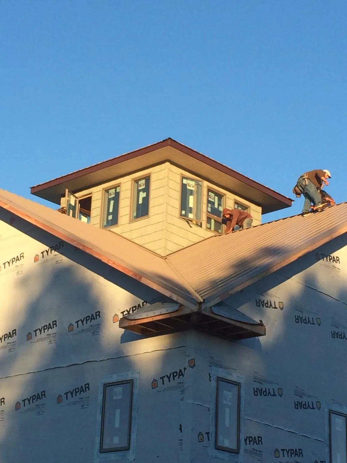 Roofers working around a rooftop cupola on a new metal roof at sunset — Roof Waterproofing in Millerstown by Roofing Brothers